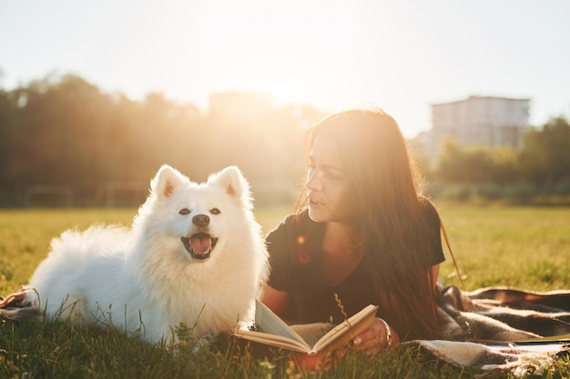 Женщина со своей собакой веселится на поле в солнечный день Красивое солнце