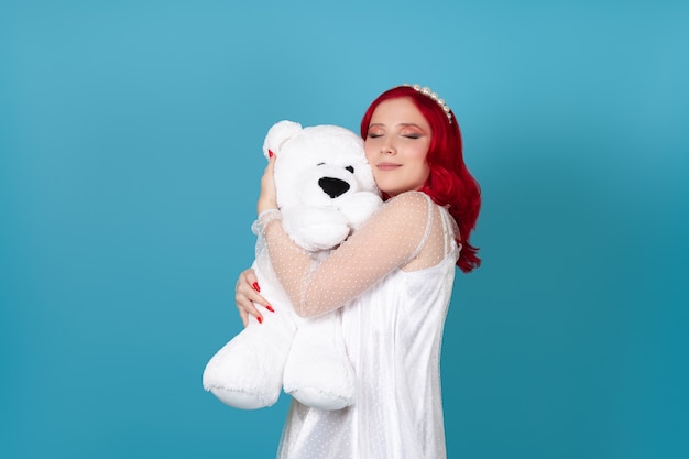 woman with her eyes closed gently presses her cheek to the muzzle of a white teddy bear