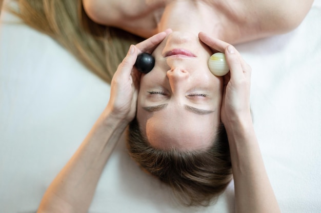 A woman with her eyes closed and her hands on her head are touching a woman's face.