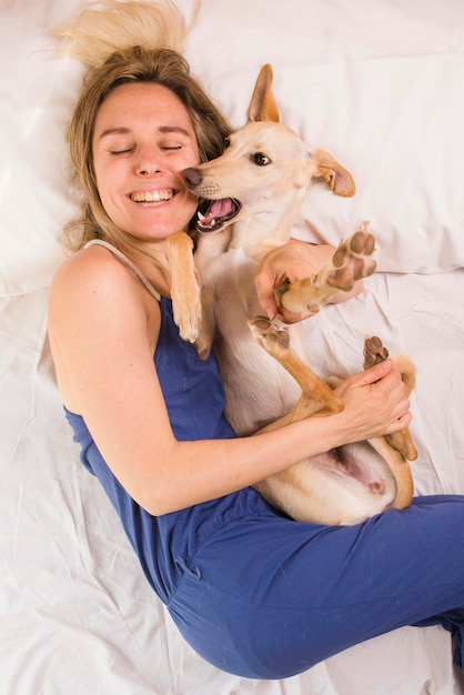 Woman with her greyhound dog in white bed