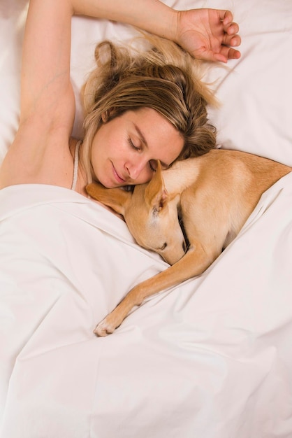 Woman with her greyhound dog in white bed