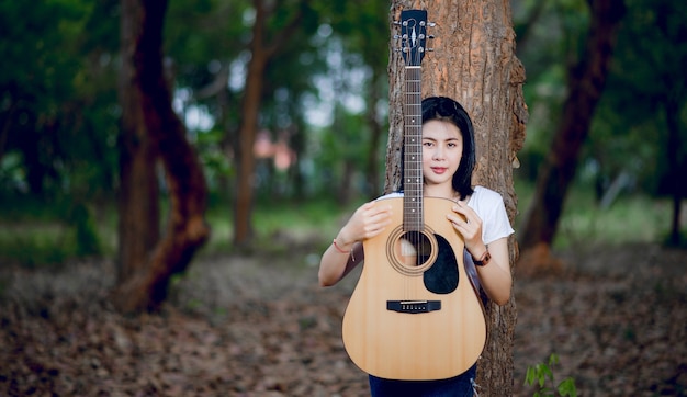 自然の中で歌っている彼女のギターを持つ女性