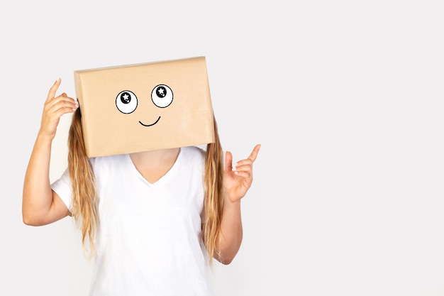 Woman with her head in a box and happiness gesture drawn on it with raised fingers