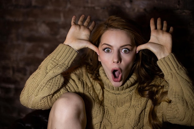 Photo a woman with her mouth open and her hands on her head are on the floor.