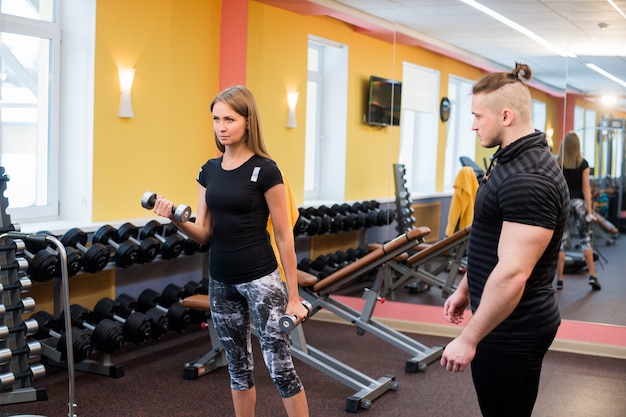 Фото Женщина с ее личным тренером по фитнесу в тренажерном зале, осуществляющих силовую гимнастику со штангой
