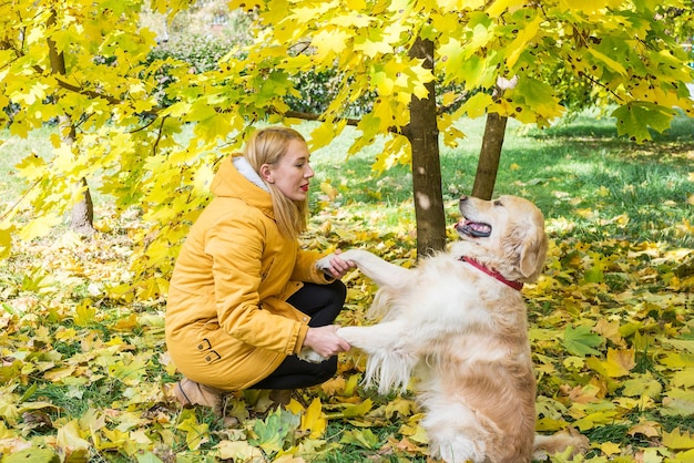 Woman with her retriever in the park in autumn