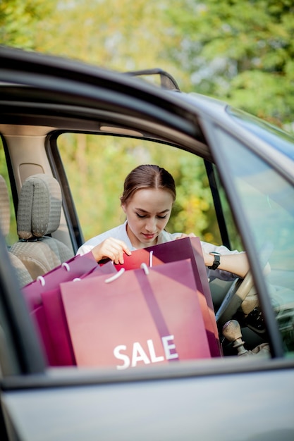 車の買い物の概念に彼女の買い物袋を持つ女性