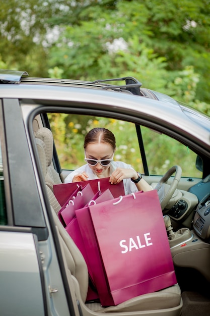 車の買い物の概念に彼女の買い物袋を持つ女性。