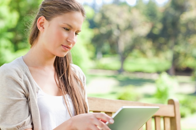 Woman with her tablet computer sitting on a park bench