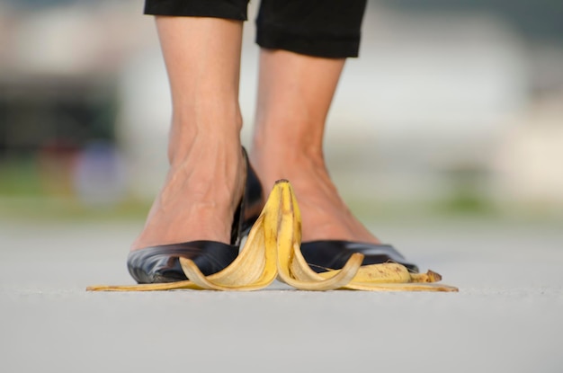 バナナの皮の前に立っているハイヒールを履いた女性