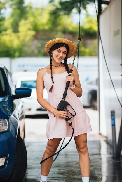 Woman with high pressure hose at car wash