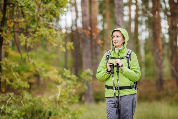 Woman with hiking equipment walking in forest