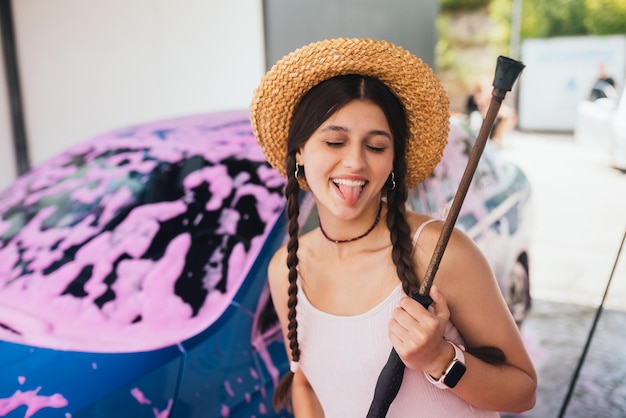 Woman with hose stands near car covered in pink foam