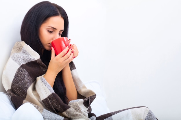 Woman with hot tea in bed