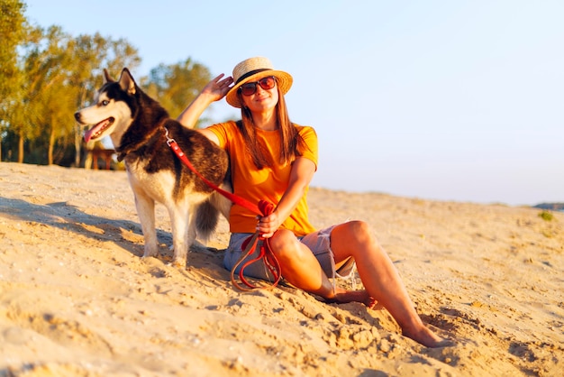 Woman with husky dog enjoying beach sunset