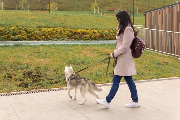 Donna con cane husky che cammina nel parco autunnale