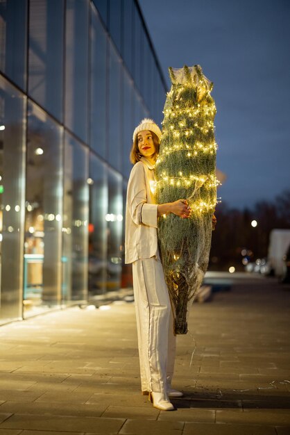 ショッピングセンターの近くに照らされたクリスマスツリーを持つ女性