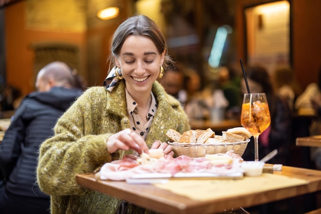 Woman with italian snacks and drink at bar outdoors