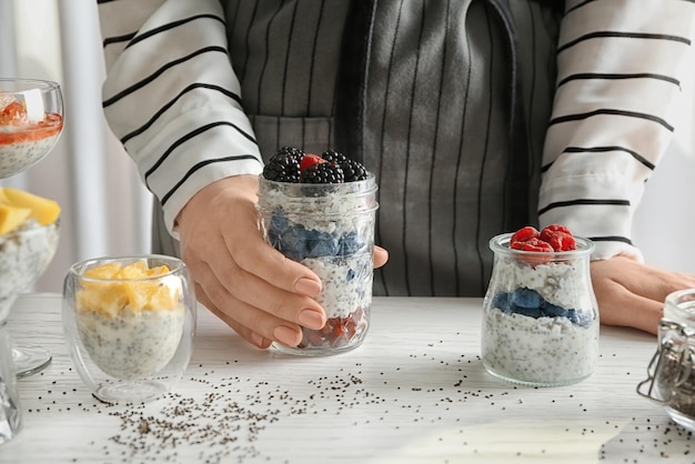 Woman with jar of delicious chia seed pudding at table