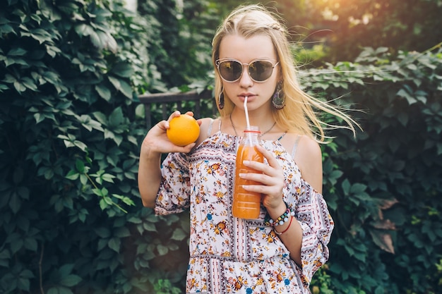 Woman with juice posing at fence