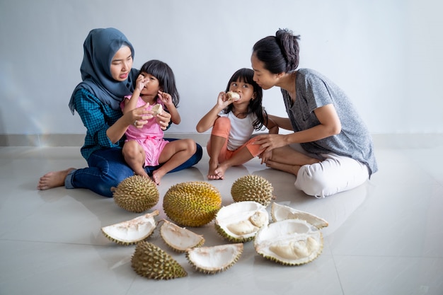 ドリアンの果実を食べる子供を持つ女性