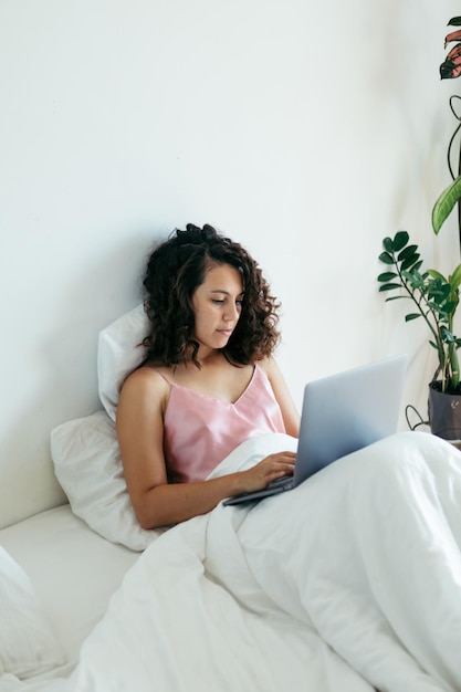 Woman with laptop in bed freelancer internet shopping