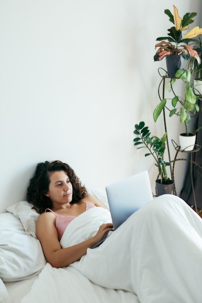 Woman with laptop in bed freelancer