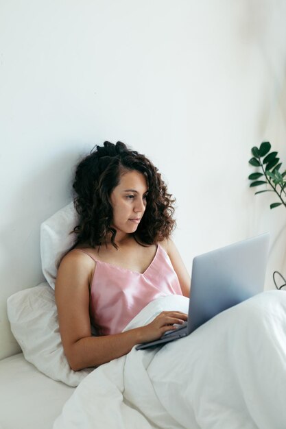 Foto donna con laptop a letto freelance