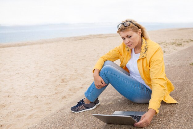 Photo a woman with a laptop by the lake in the summer