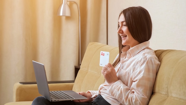 Woman with laptop demonstrates postcards with letters of the English alphabet and pronounce sounds and words.