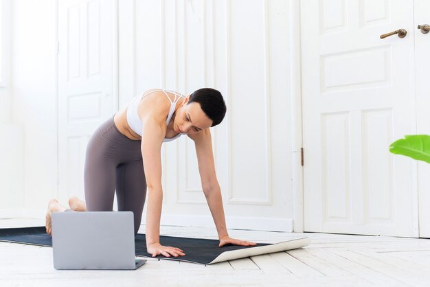 Woman with laptop doing yoga at home