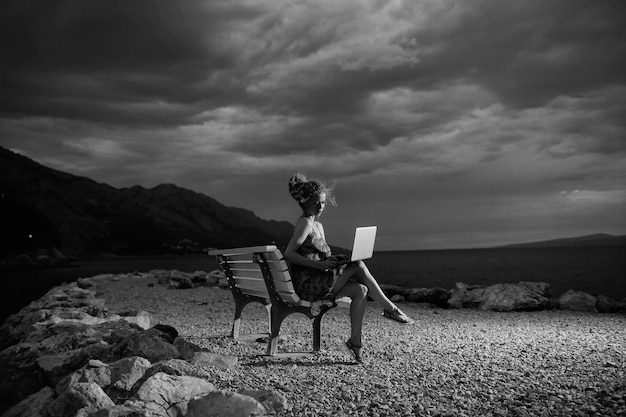 Woman with laptop on evening beach