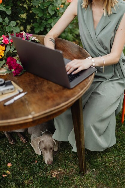 彼女の犬と一緒に働いている庭でラップトップを持つ女性