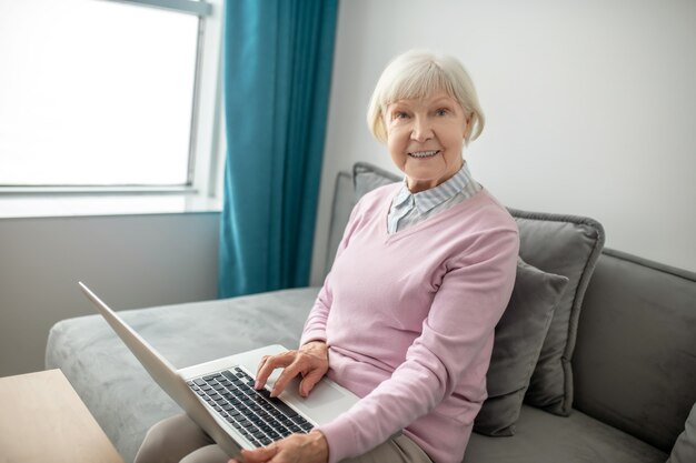 Woman with laptop. Senior woman sitting in front of laptop and looking contented