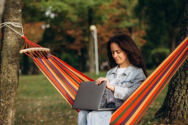 Woman with laptop sitting in hammock