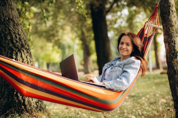 Woman with laptop sitting in hammock