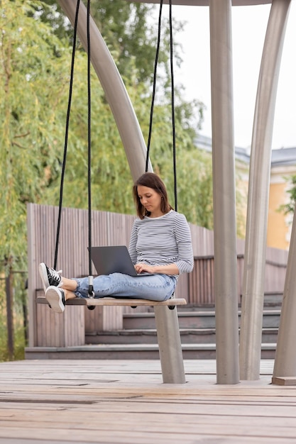 Фото Женщина с ноутбуком сидит на качелях