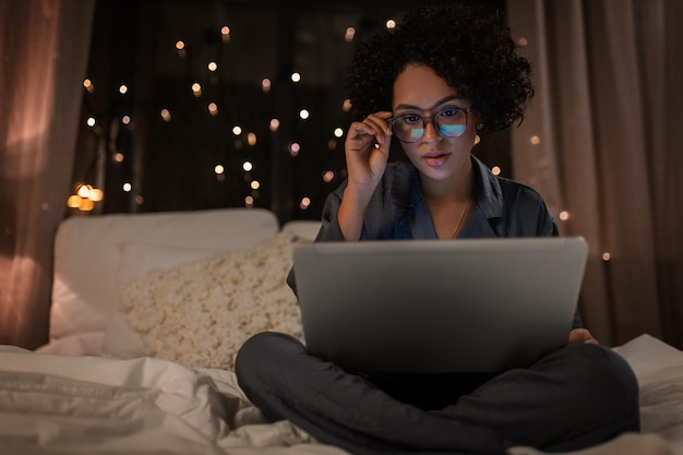 woman with laptop working in bed at night