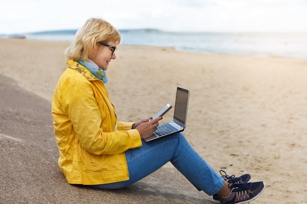 Woman with laptop working outdoors on the river bank concept freelance