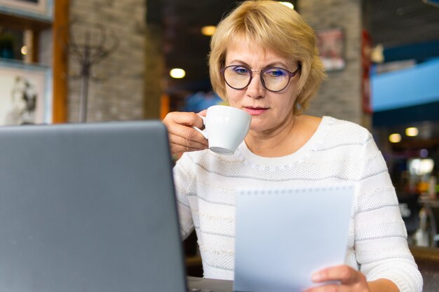 Woman with a laptop works in a cafe in the office, she is a freelancer