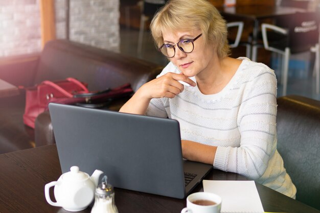 Woman with a laptop works in a cafe in the office, she is a freelancer.