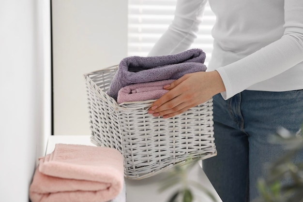 Woman with laundry basket of clean towels indoors closeup