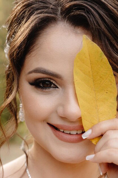 Photo a woman with a leaf on her face is holding a leaf