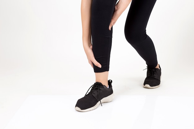 Woman with leg feeling pain. Studio shot on white background.  Fitness and health concept 