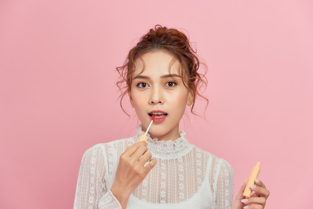 Photo woman with lip gloss. photo of woman with perfect makeup on pink