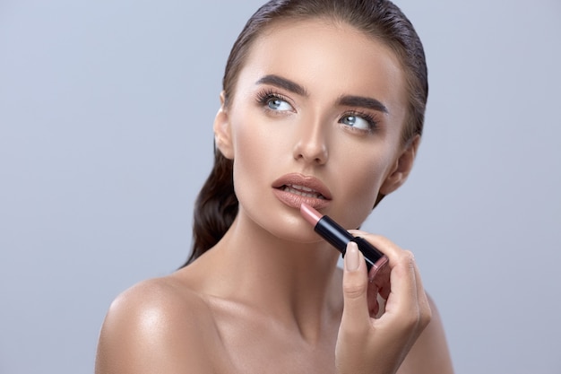 Donna con rossetto, primo piano di bellezza con rossetto, bella donna che applica rossetto e che osserva in su, bella ragazza che applica trucco