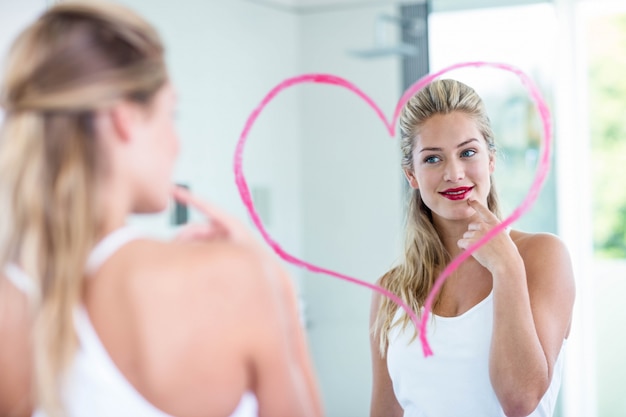 Woman with lipstick looking in the mirror in the bathroom