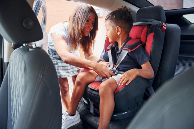 Woman with little boy is in the modern automobile at daytime