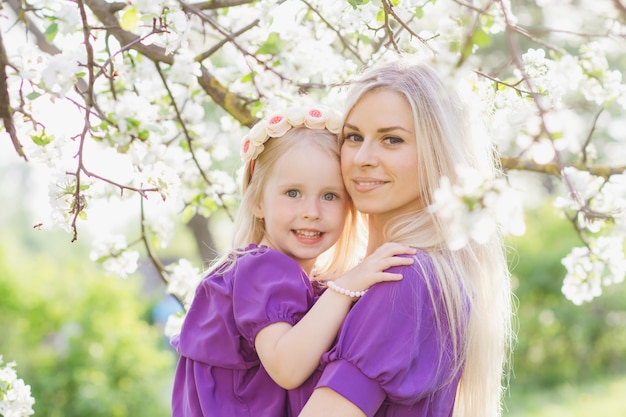 Woman with a little daughter walking through the blooming Apple