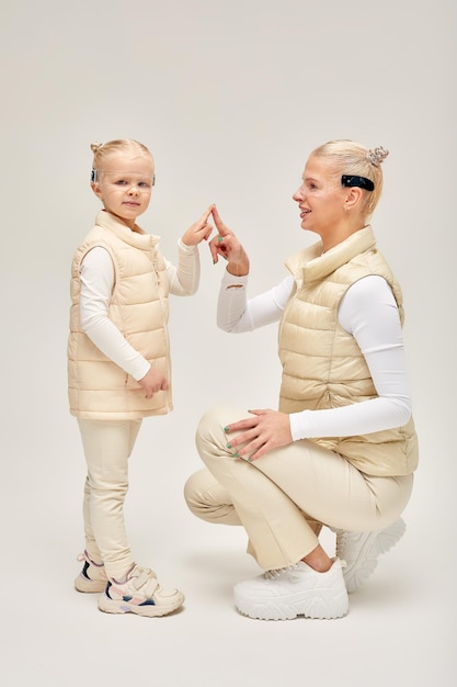 Woman with little girl in futuristic costume wearing smart led glasses of virtual reality while touching air Augmented reality game future technology AI concept VR